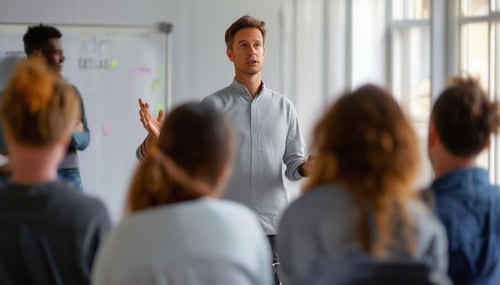Size 335 x 175 Subject Faciliting workshopsEnvironment Faciliting a workshop in front of a group people standing upLighting Focussed on the facilita-1